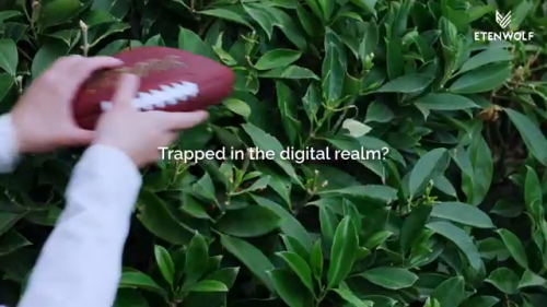 ETENWOLF - Escape the Digital Realm Person holding a football outdoors with text Trapped in the digital realm ETENWOLF brand message