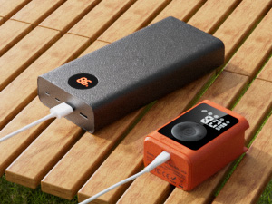 ETENWOLF P300 Plus electric ball pump being charged by a portable power bank via USB-C cable on a wooden outdoor table.