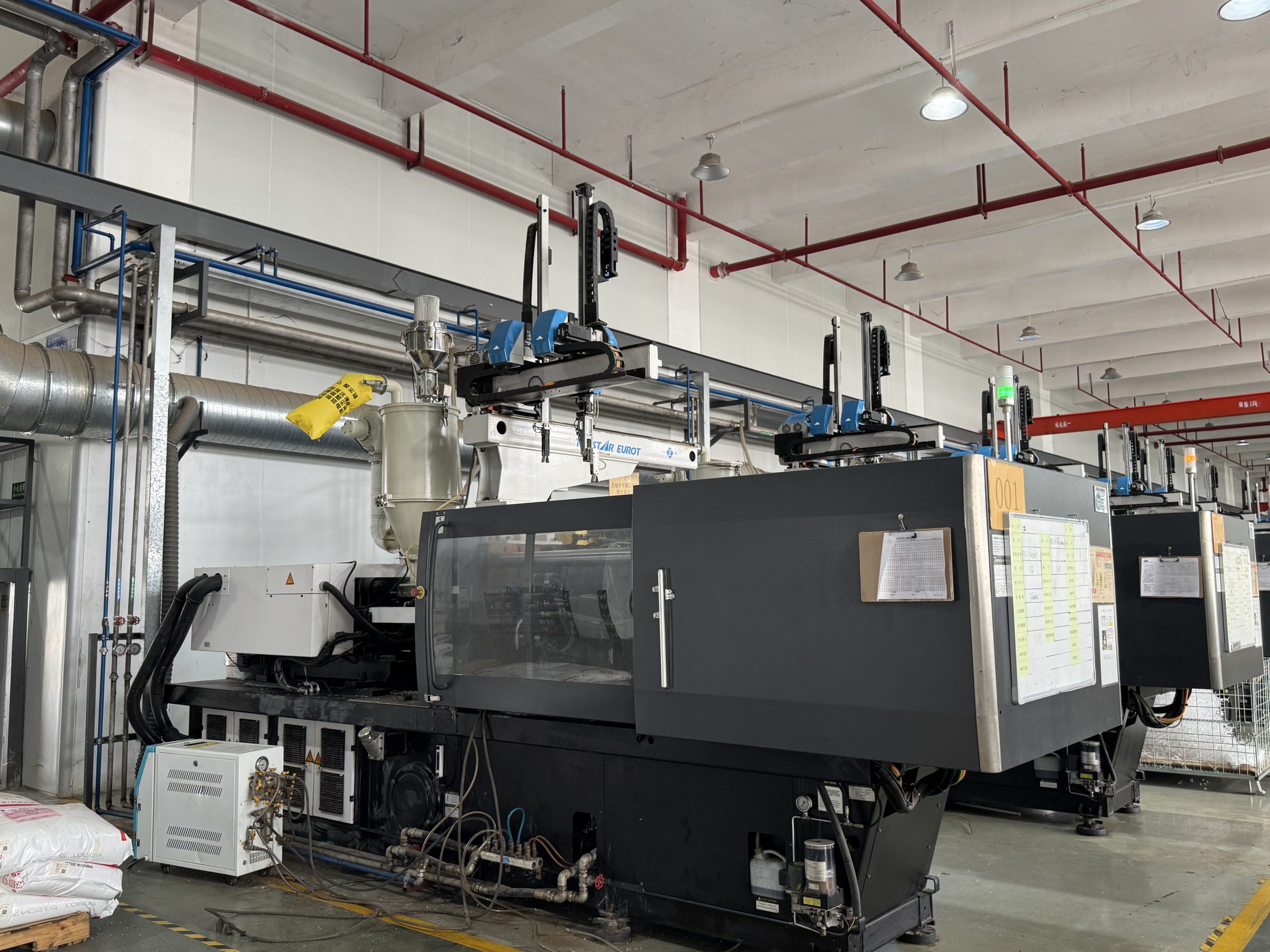 Heavy-duty injection molding machinery with automated robotic arms in a clean industrial factory workshop