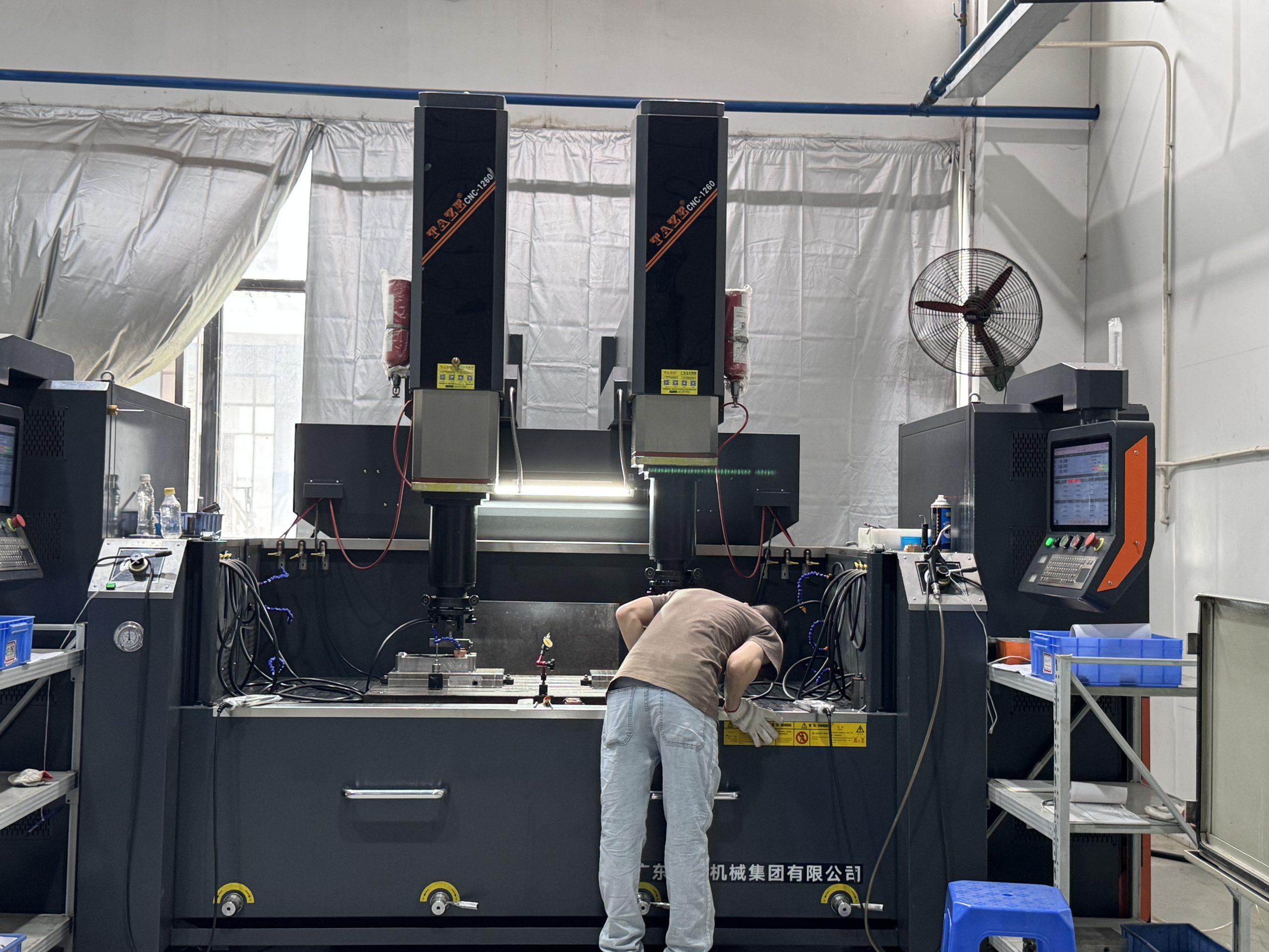 Two technicians discussing mold blueprints and control panel parameters in front of the TAZE CNC-1260 CNC EDM machine at ETENWOLF workshop.