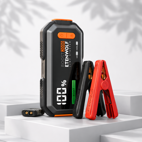 ETENWOLF J1 portable jump starter with battery clamps displayed beside a vehicle in an outdoor roadside emergency setting
