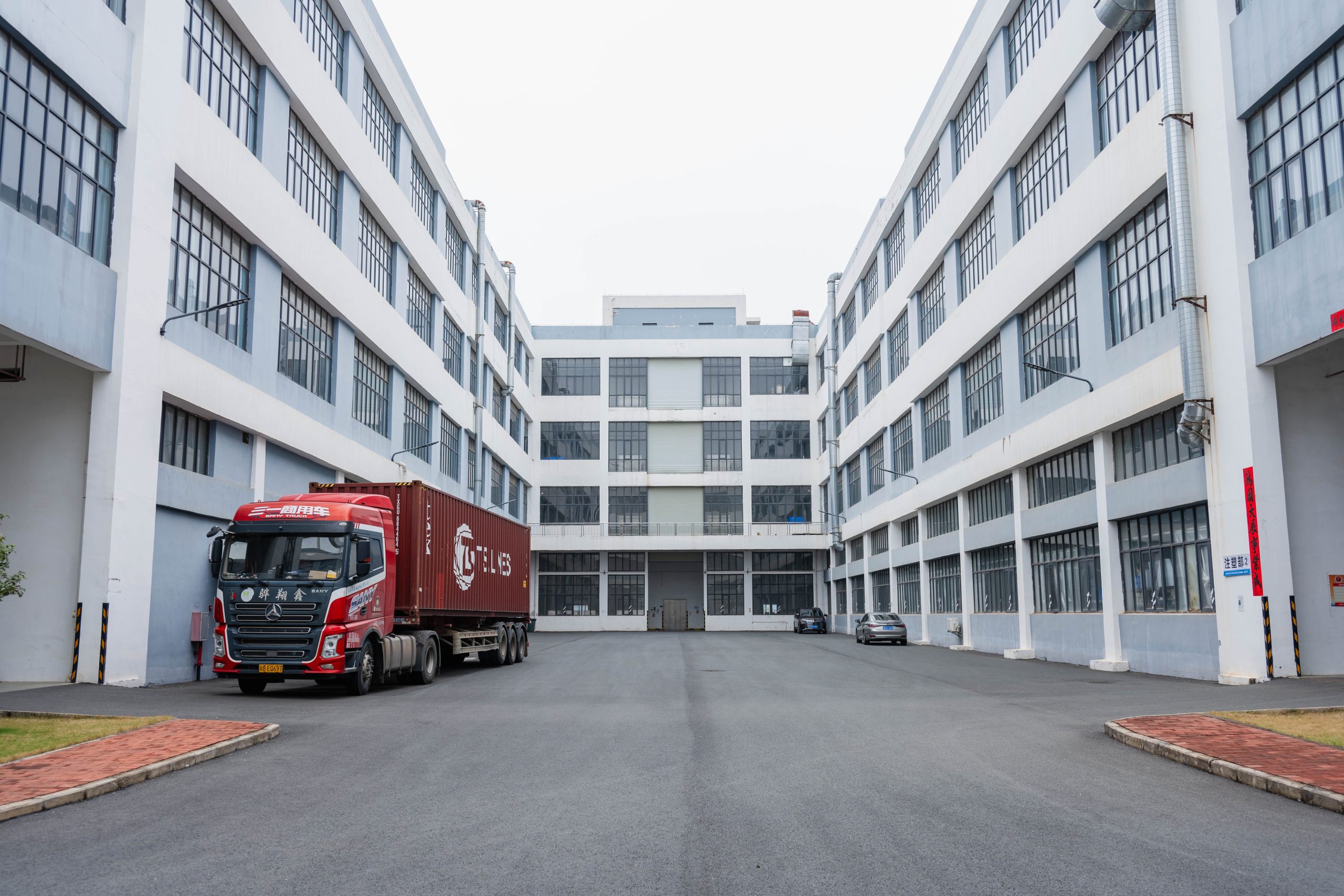 Exterior view of the ETENWOLF manufacturing plant and production base with a logistics truck loading automotive electronic supplies.