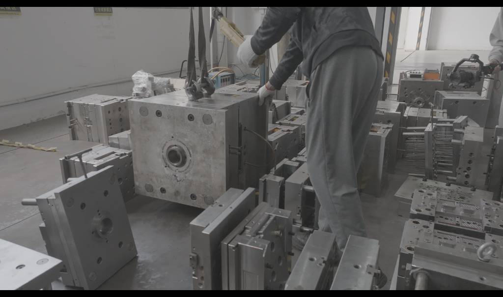 A worker holding a mold lifted by a gantry crane in the ETENWOLF factory.