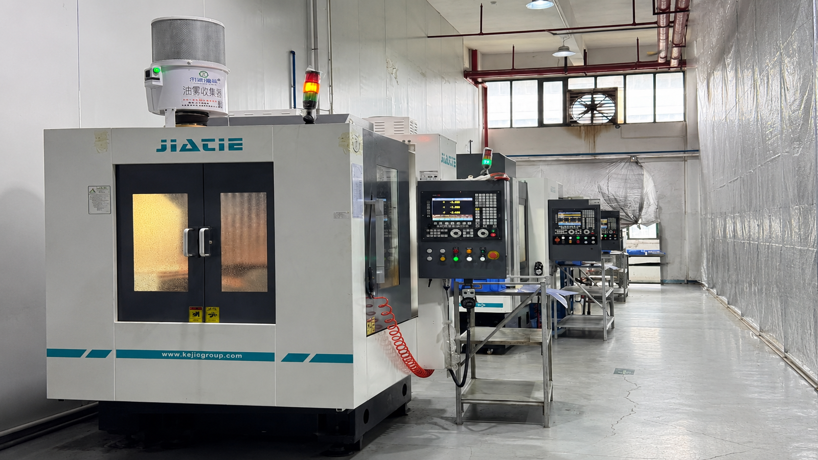 Overall view of high-speed CNC milling machines running in an industrial workshop enclosure.